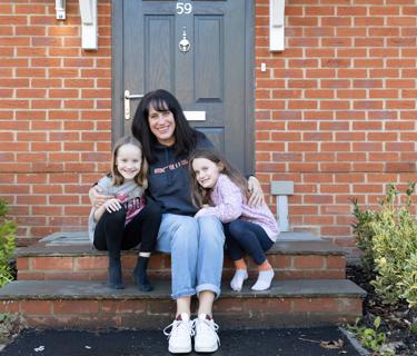 Resident and her two daughters sitting outside their new shared ownership property