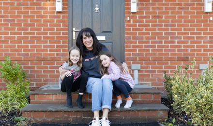 Resident and her two daughters sitting outside their new shared ownership property