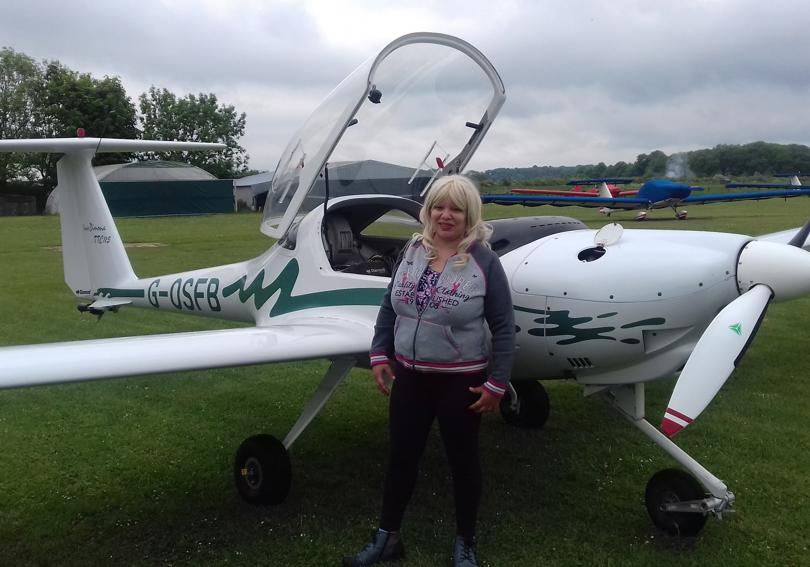 Woman standing in front of a white and green plane in a field