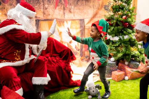 Santa Clause high fiving a child in an elf costume