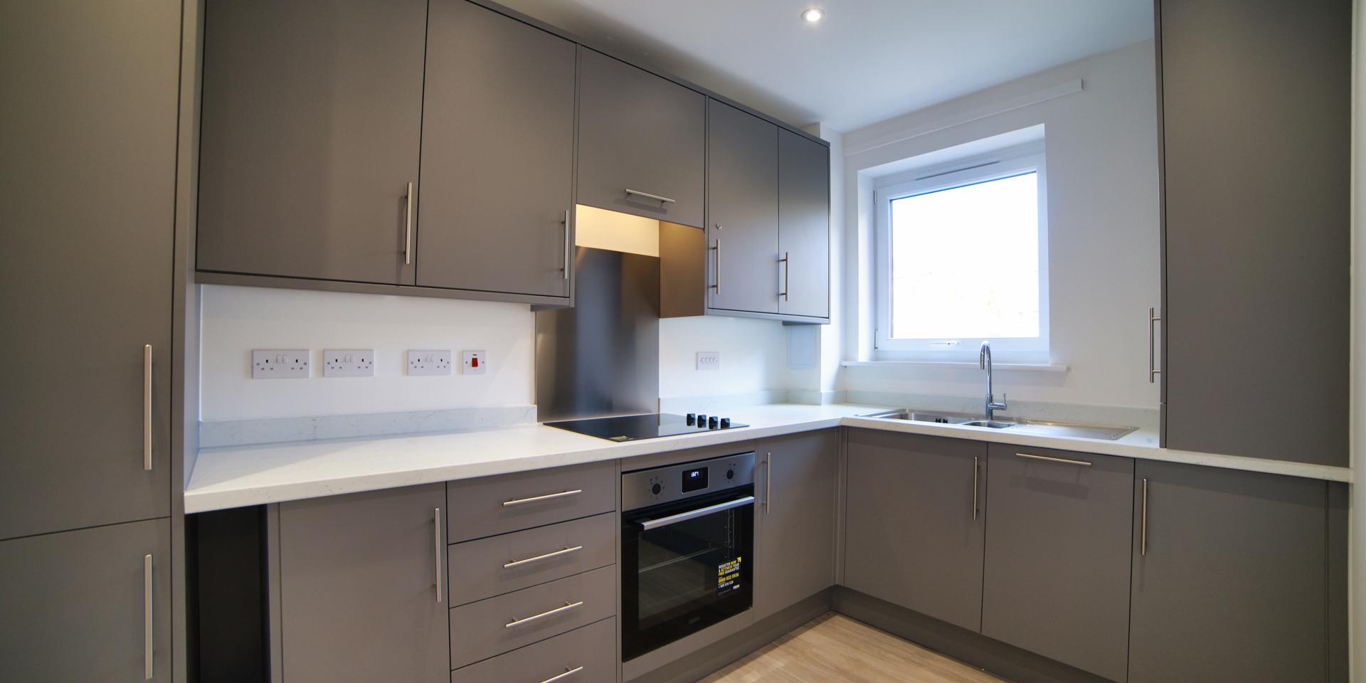 The kitchen is a modern grey colour and comes with electric oven and ceramic electric hob