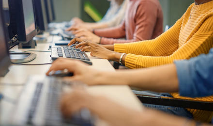 A row of people's hands, typing on a computer.