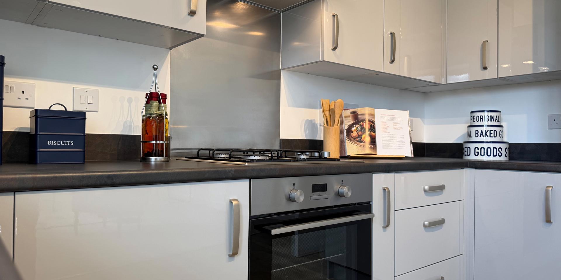The kitchen has grey gloss units and a built-in electric cooker and gas hob
