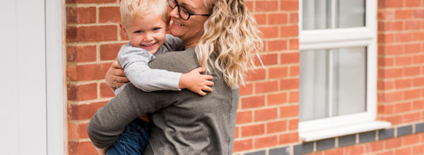 Resident and her young son smiling and laughing outside their home