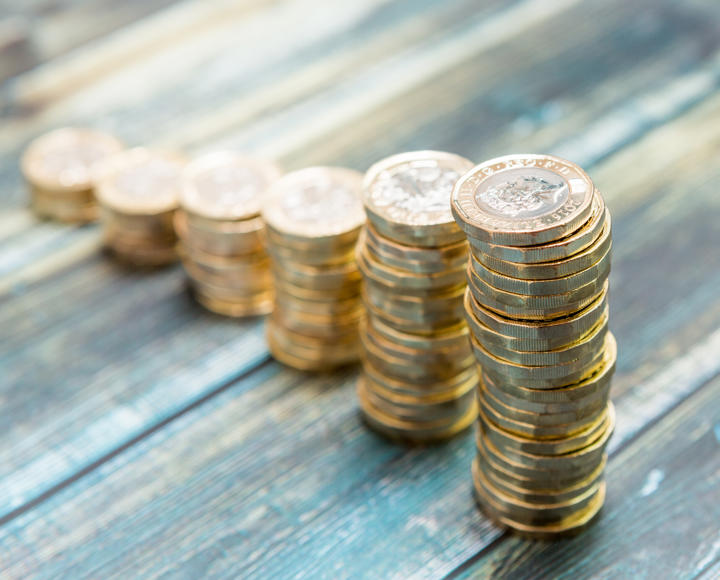 Multiple piles of £1 coins, descending in order