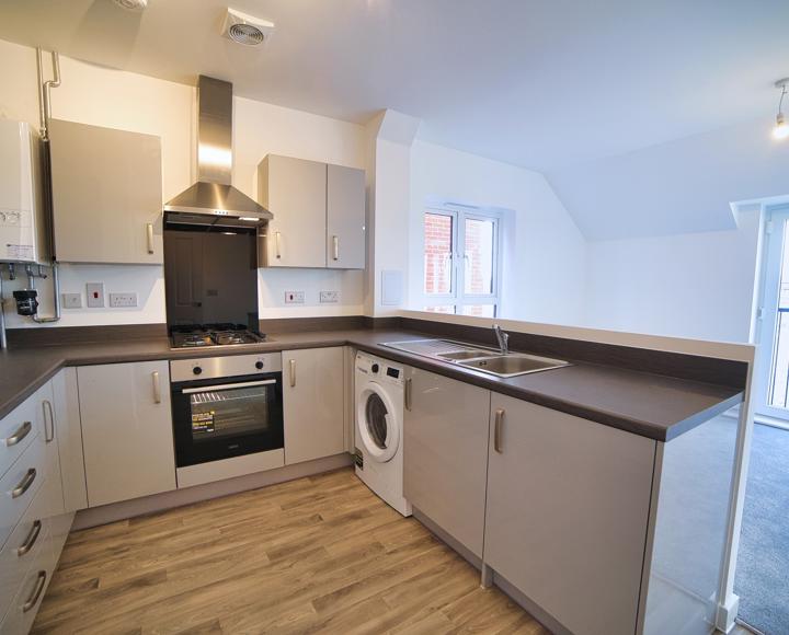 An image of the fitted kitchen with its built-in oven and hob and freestanding washer dryer