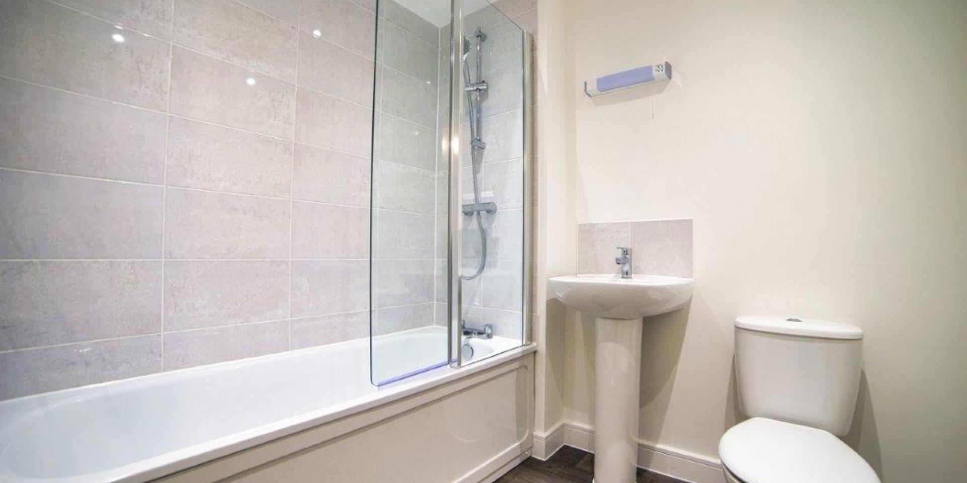 Image of bathroom showing the bath with its shower, wash hand basin and toilet