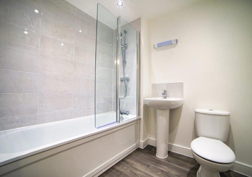 Image of bathroom showing the bath with its shower, wash hand basin and toilet