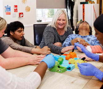 Service users and staff members playing hungry hippos together at a table
