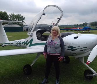 A care and supported housing resident standing near a small plane before her flying lessons