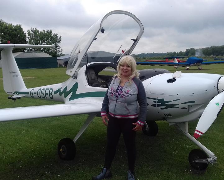 A care and supported housing resident standing near a small plane before her flying lessons