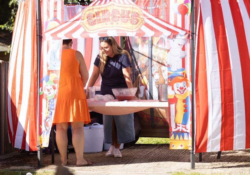 Staff serving drinks out of a punch bowl, in a circus tent