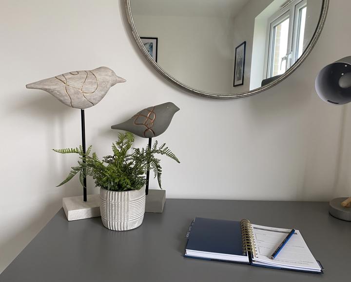 Two bird ornaments on top of a desk with a note pad