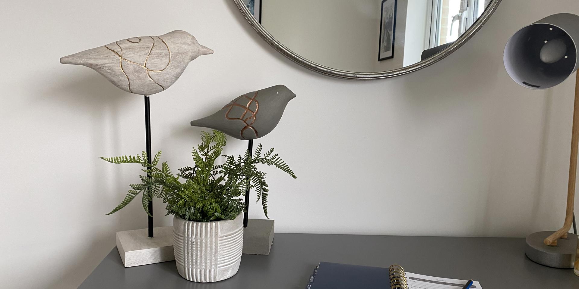 Two bird ornaments on top of a desk with a note pad