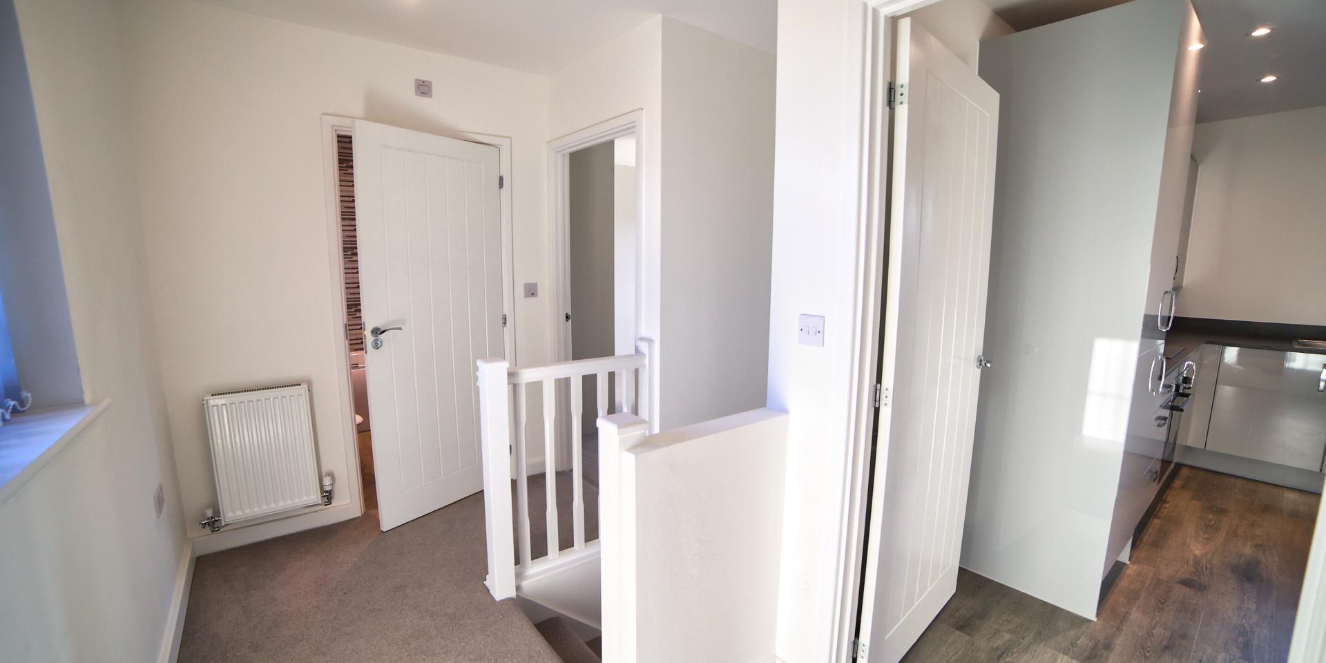 A view of the landing showing the doorway to the bathroom and kitchen diner
