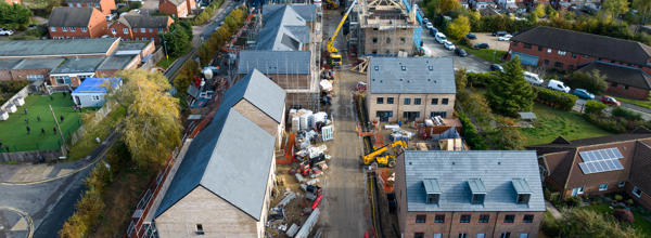 New build houses are being built. They are built but the surroundings are a building site, with cranes and building materials around.