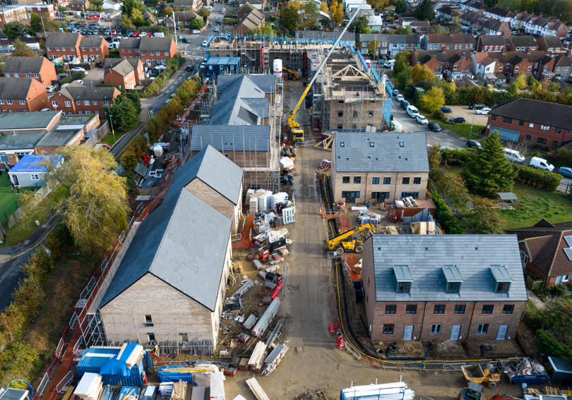 New build houses are being built. They are built but the surroundings are a building site, with cranes and building materials around.