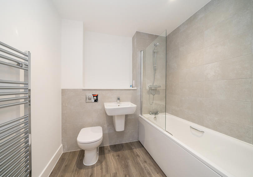 Photo of the bathroom showing the bath with thermostatic shower, wash hand basin and toilet