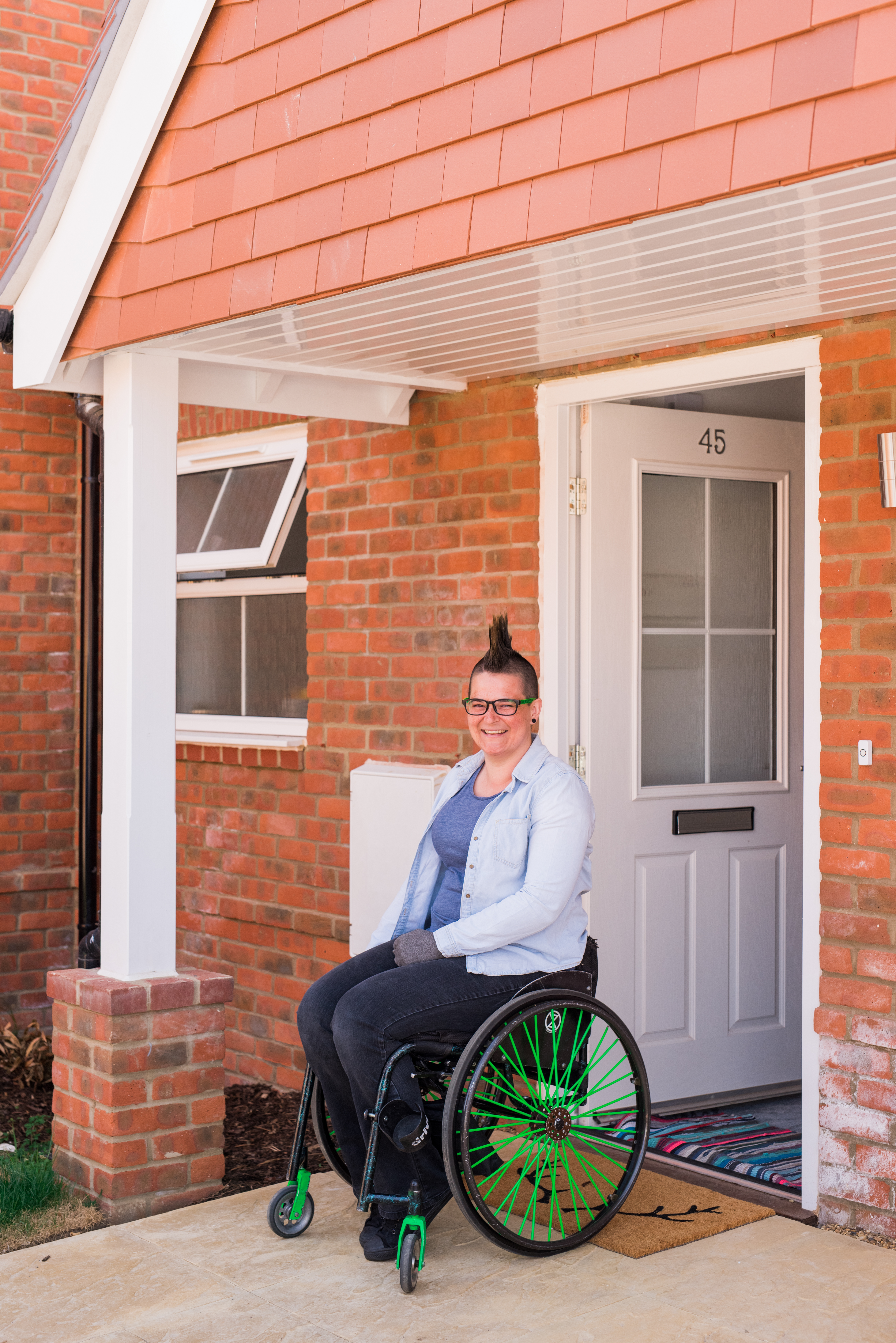 A women in her wheelchair in at the front door of her home.