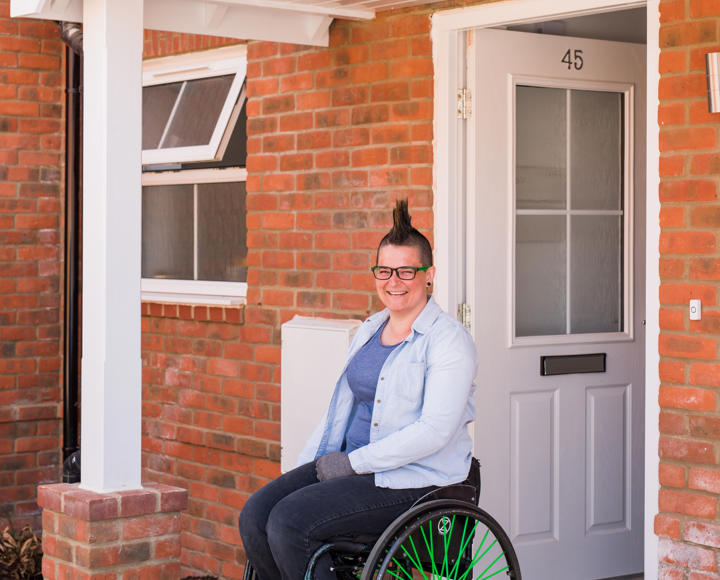 A women in her wheelchair in at the front door of her home.