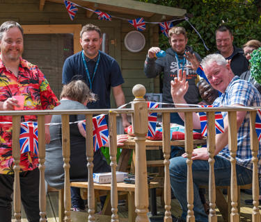 Care and supported housing staff and service users enjoying a party outside on a sunny day. 