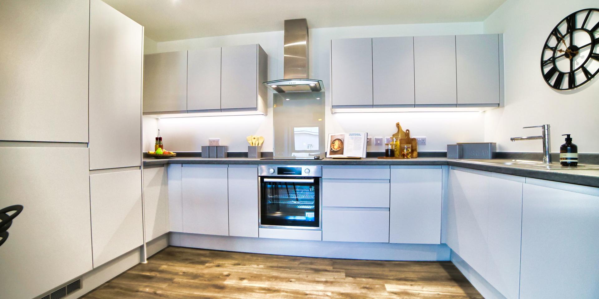 Fully fitted kitchen with integrated appliances and handless grey units