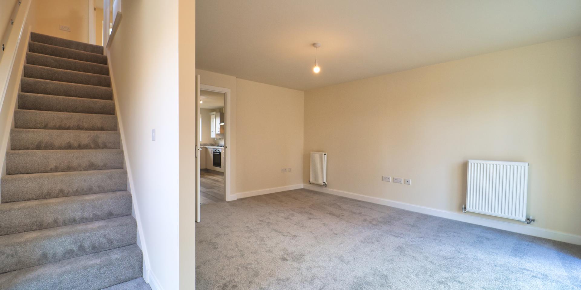 A good sized living room with grey carpets
