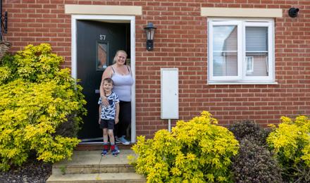 A mother and son stood in the front doorway of their home.