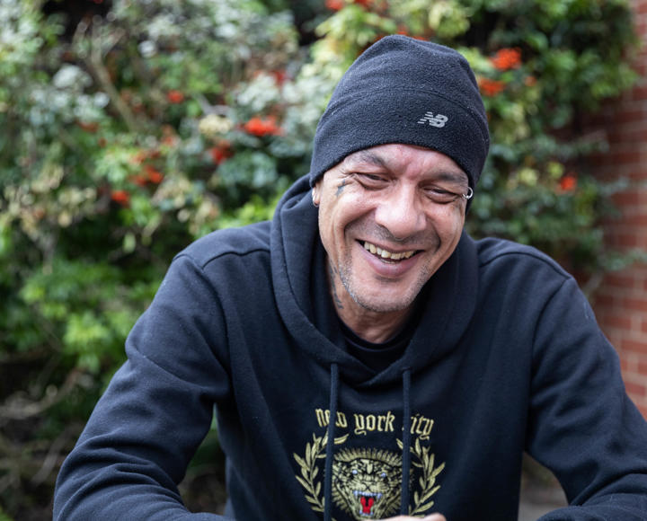 Man outside with black hoodie and hat on laughing