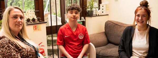 Hightown staff member and two young people smiling in living room