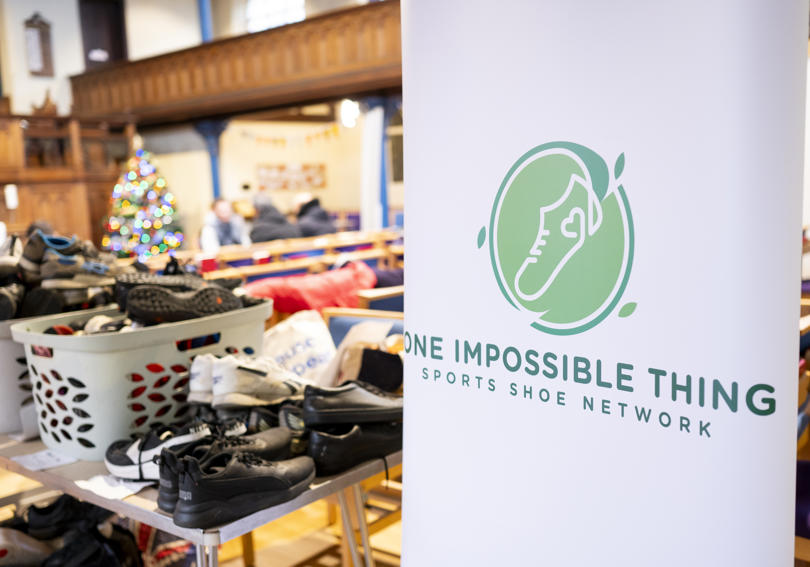 An image of One Impossible Thing's banner, and a box of donated shoes.