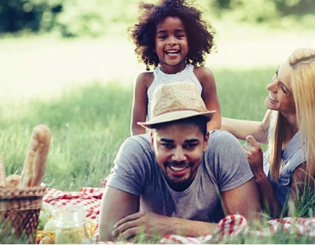 A stock image showing a family on a picnic blanket enjoying a picnic