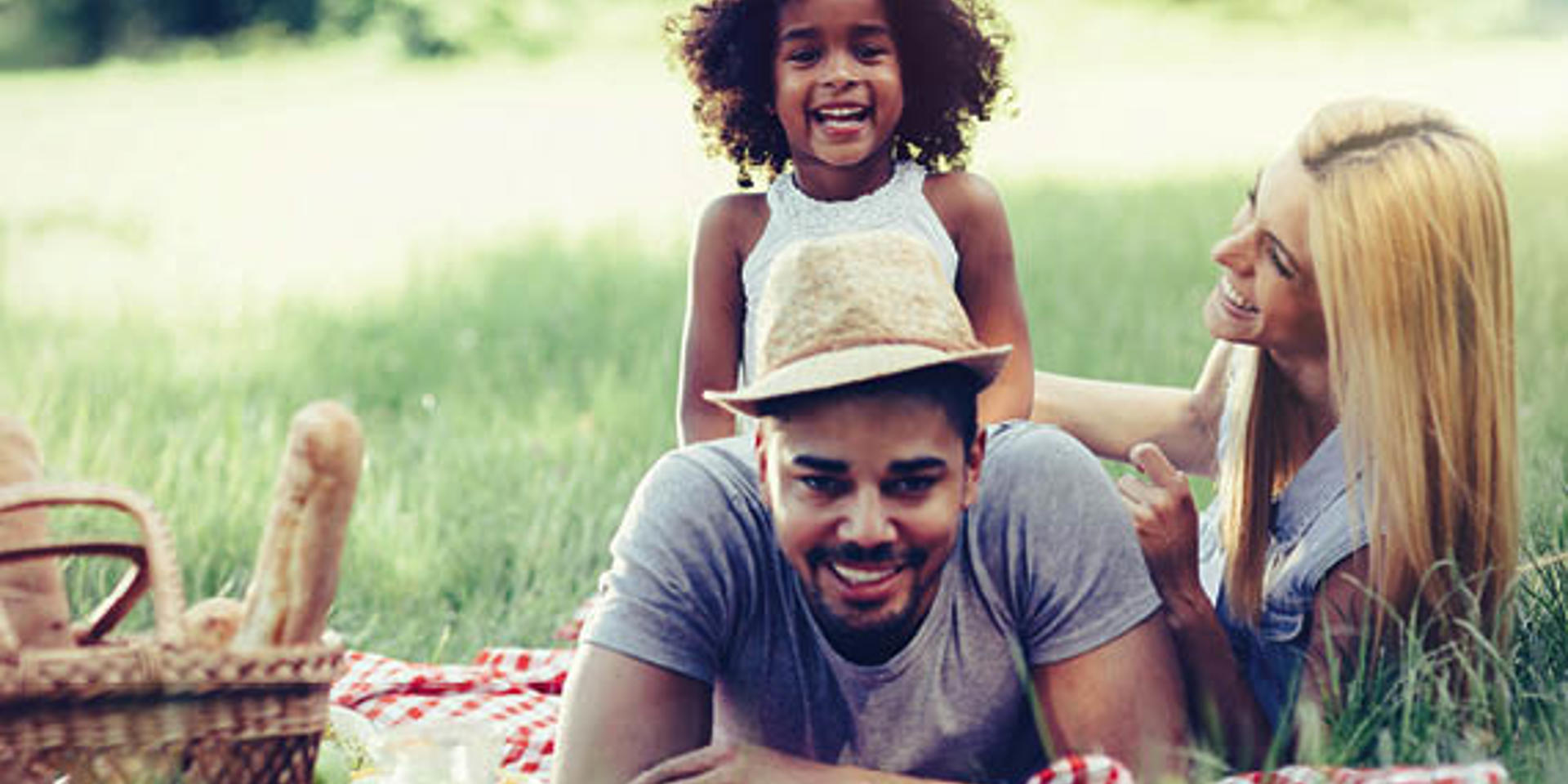 A stock image showing a family on a picnic blanket enjoying a picnic