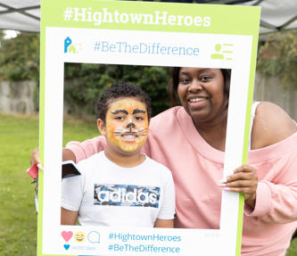 Hightown resident and her son in facepaint and posing with a selfie frame at a summer resident involvement event