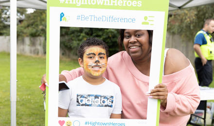 Hightown resident and her son in facepaint and posing with a selfie frame at a summer resident involvement event