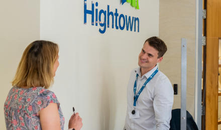 A member of staff talking to a resident at reception in Hightown's office