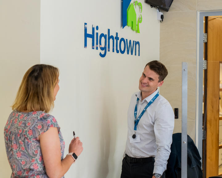 A member of staff talking to a resident at reception in Hightown's office
