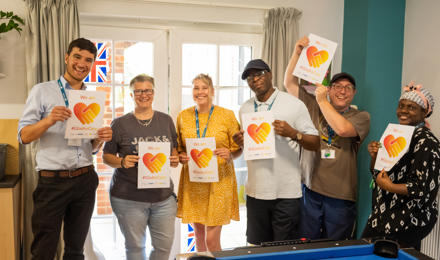 Staff standing and smiling holding #GladtoCare signs