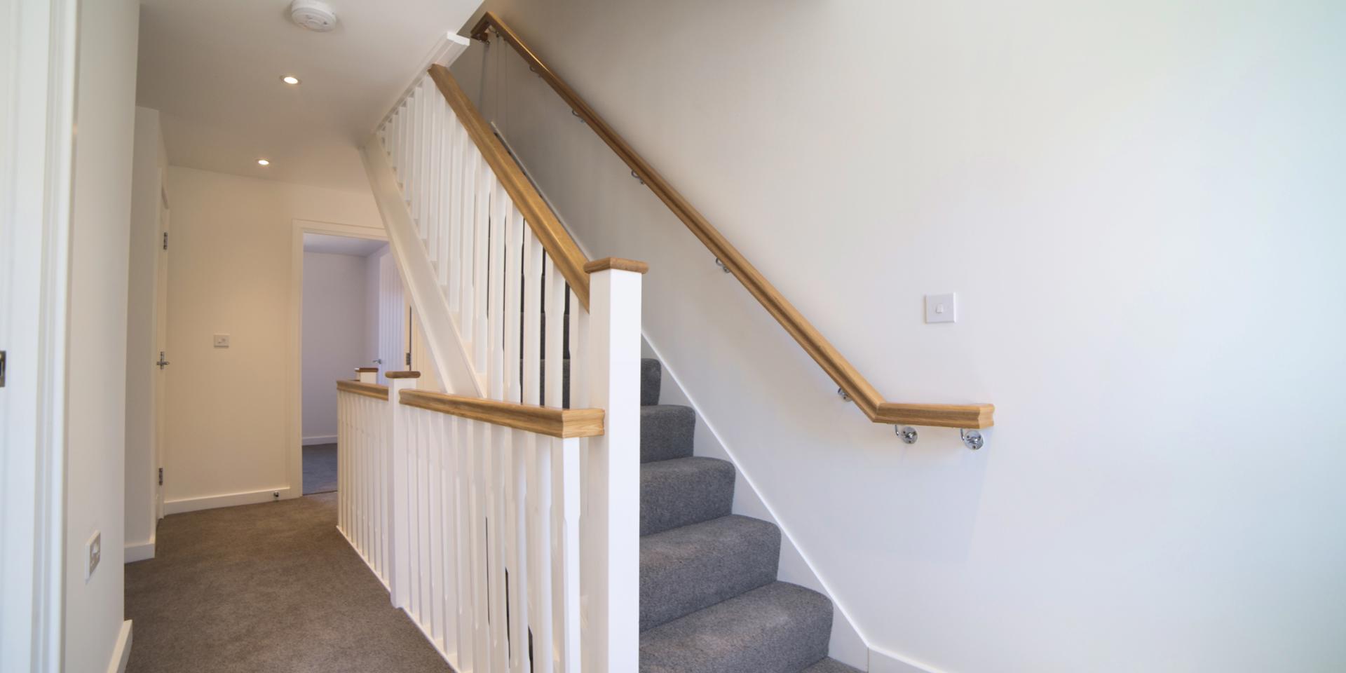 There is grey carpet to the stairs and landing as well as a wooden handrail.