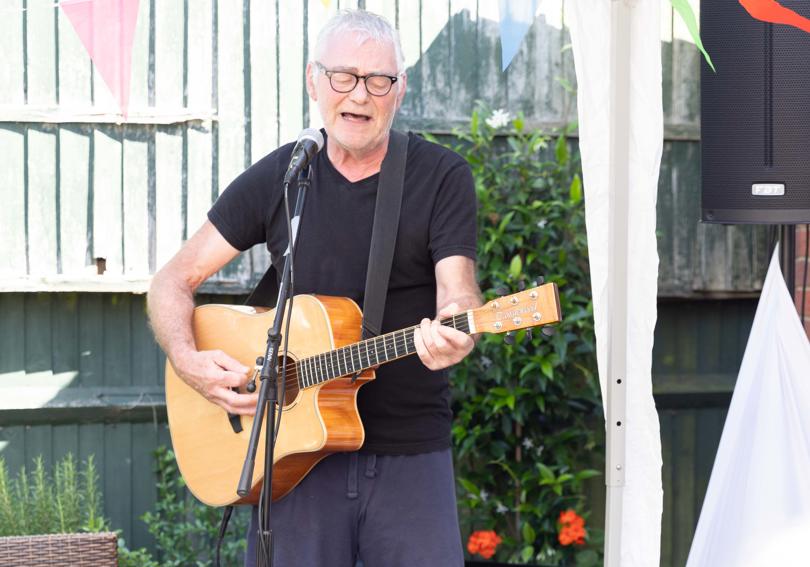 A man singing and playing acoustic guitar in the garden