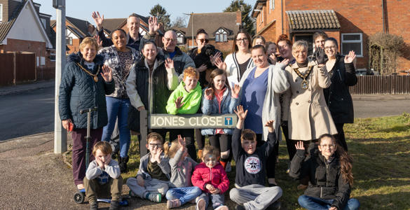 A large group of people stood in front of a road name, which is 'Jones Close'.