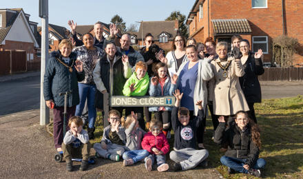 A large group of people stood in front of a road name, which is 'Jones Close'.