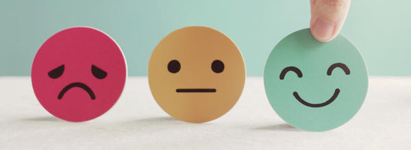 A picture showing a sad, indifferent and happy face. The hand is picking up and choosing the happy face to symbolise their choice to feel happy.