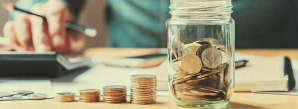 A man is counting money and storing it in a savings jar