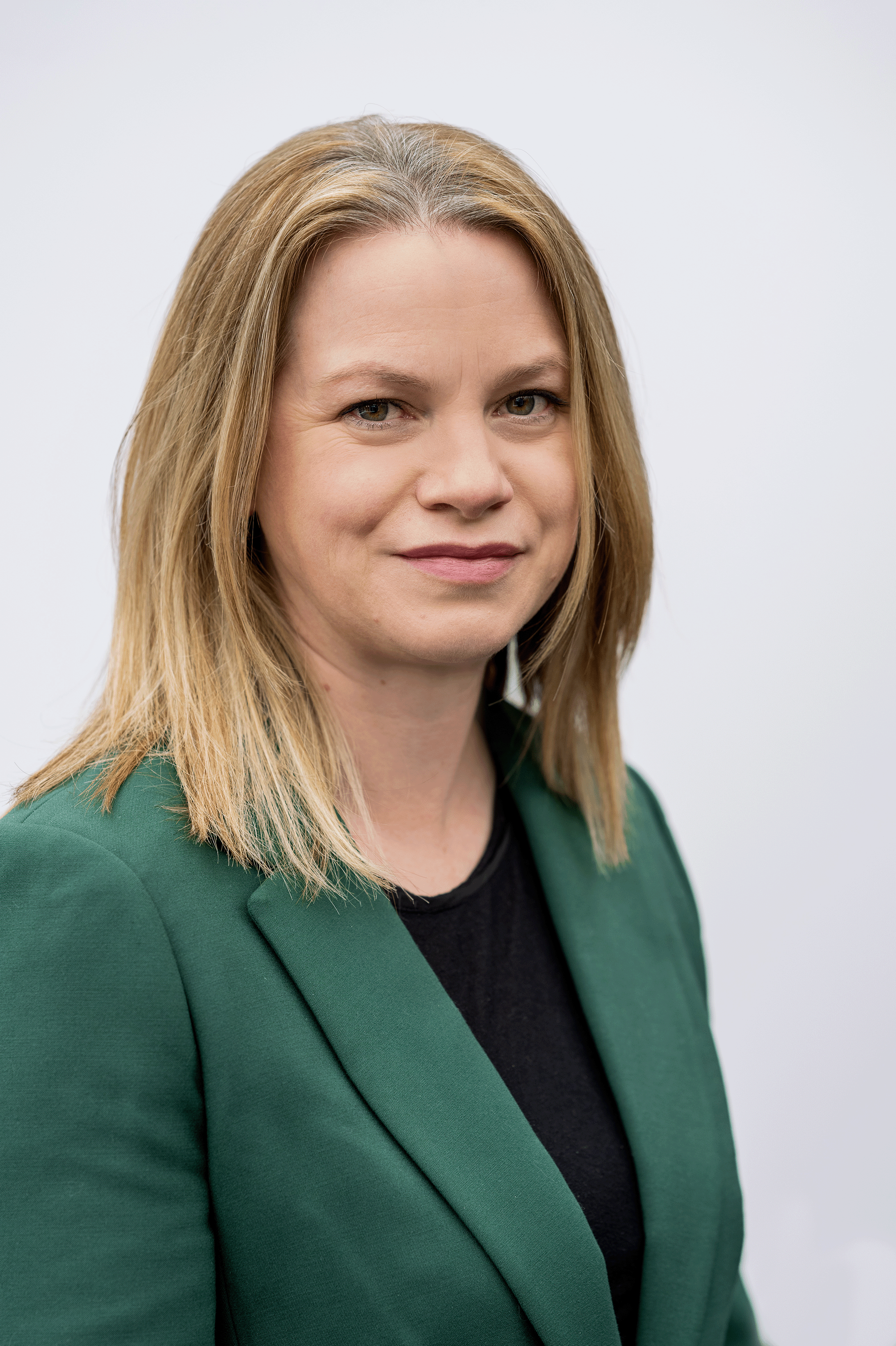 Director of housing. She is wearing an emerald green blazer with a black top. 