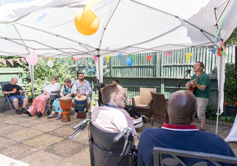 Service users in the sun watching signing and druming