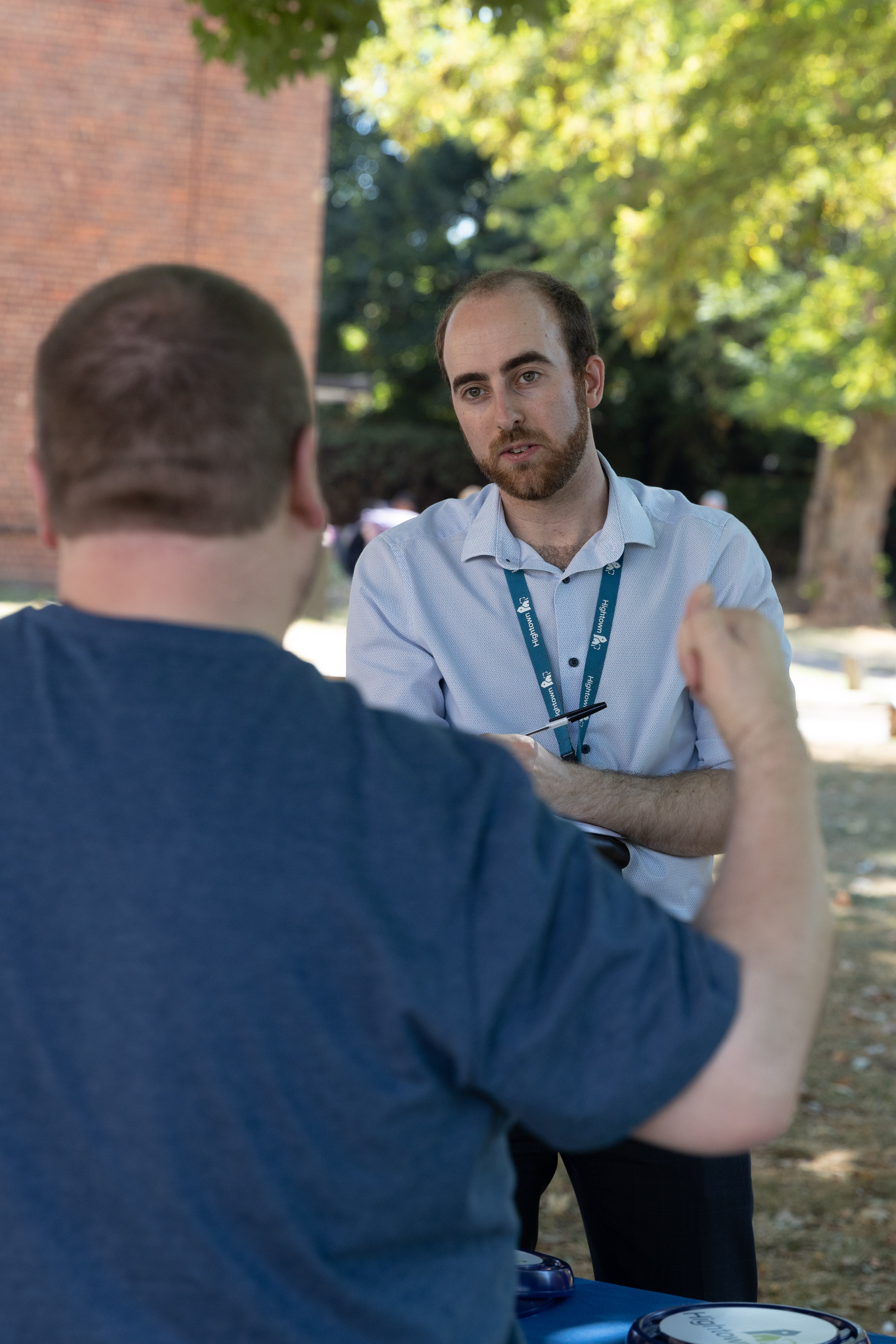 A member of staff is stood outside, listening to a resident explain something