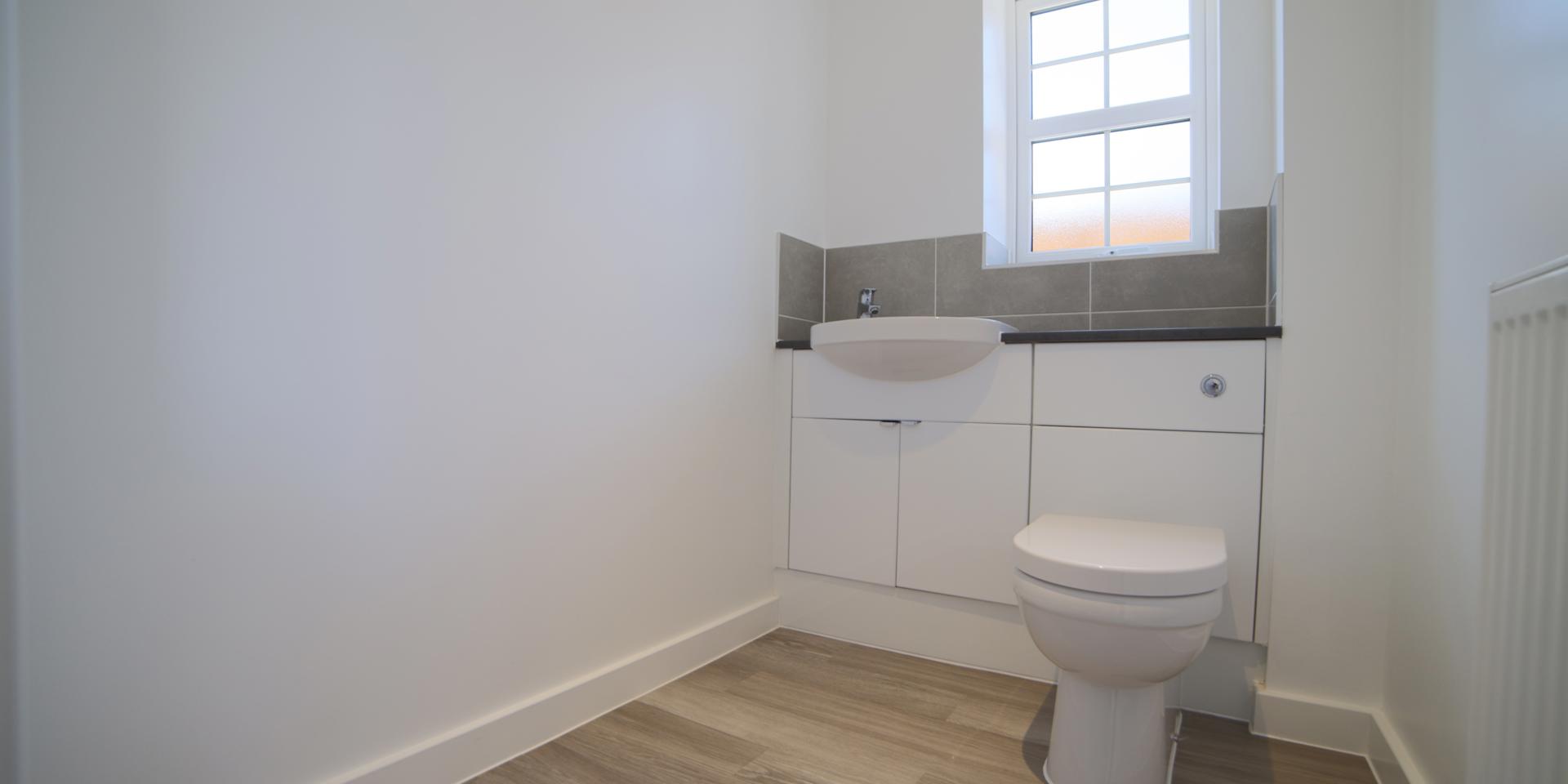 There is a downstairs cloakroom with white toilet, sink and built-in vanity unit