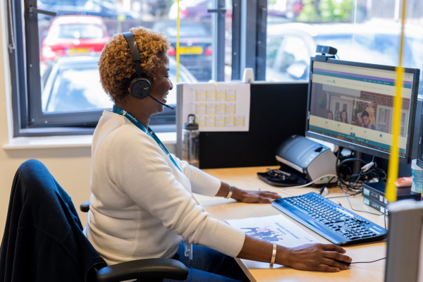 A female member of staff sat at her desk, helping a resident on the phone. 