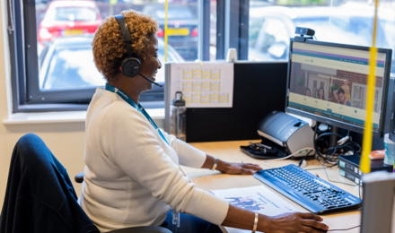 A female member of staff sat at her desk, helping a resident on the phone. 